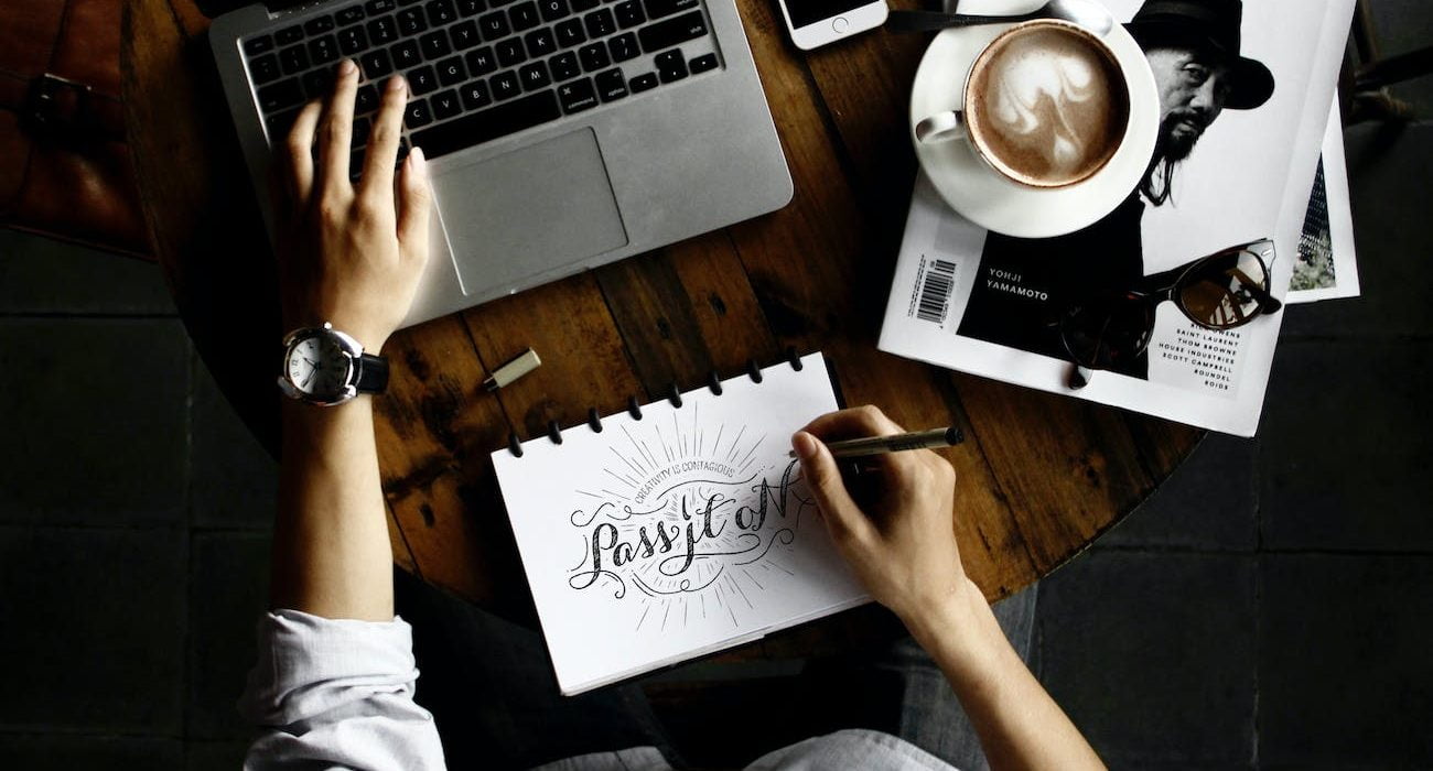 person sitting facing laptop computer with sketch pad