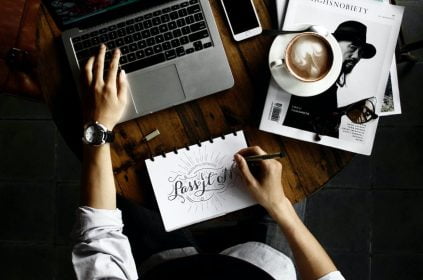 person sitting facing laptop computer with sketch pad